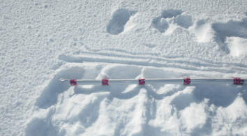 SIMBA thermistor chain with red sensor sections mounted along a horizontal support above a snow-covered surface in Greenland.
