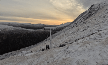 SIMBA monitoring equipment installed on a snow-covered mountainside in the Cairngorms, with support poles and equipment visible against the surrounding hills.
