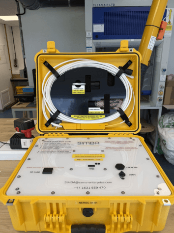 Yellow SIMBA snow- and ice monitoring device on a workbench.